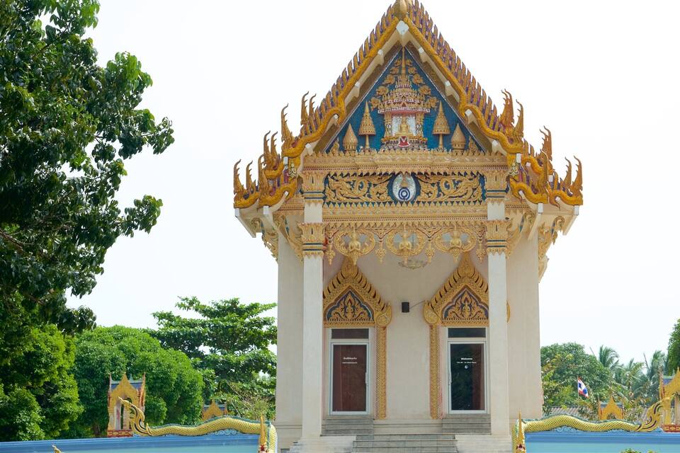 A traditional Thai temple with ornate golden decorations and a central Buddha statue.