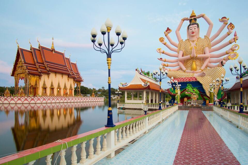 Ein Tempel mit einer großen Statue einer Gottheit, einem Spiegelbild im Wasser und traditioneller Architektur.