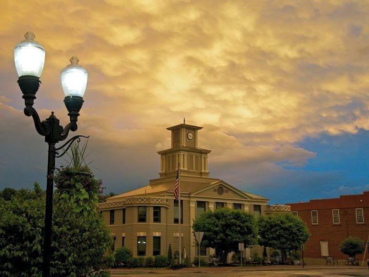 A historic building with a clock tower, surrounded by trees and a street lamp.
