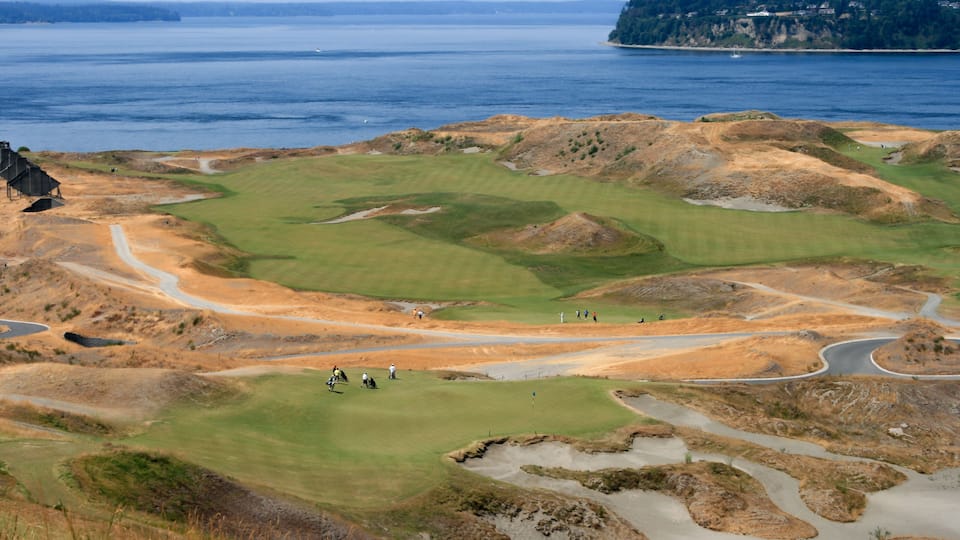 A coastal golf course with a view of the ocean and a distant island.