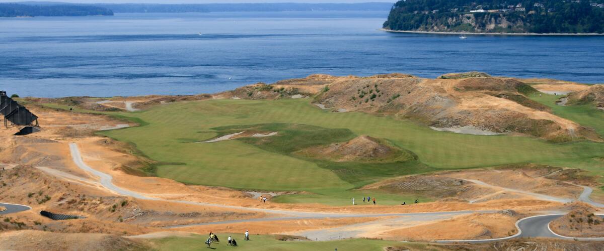 A coastal golf course with a view of the ocean and a distant island.