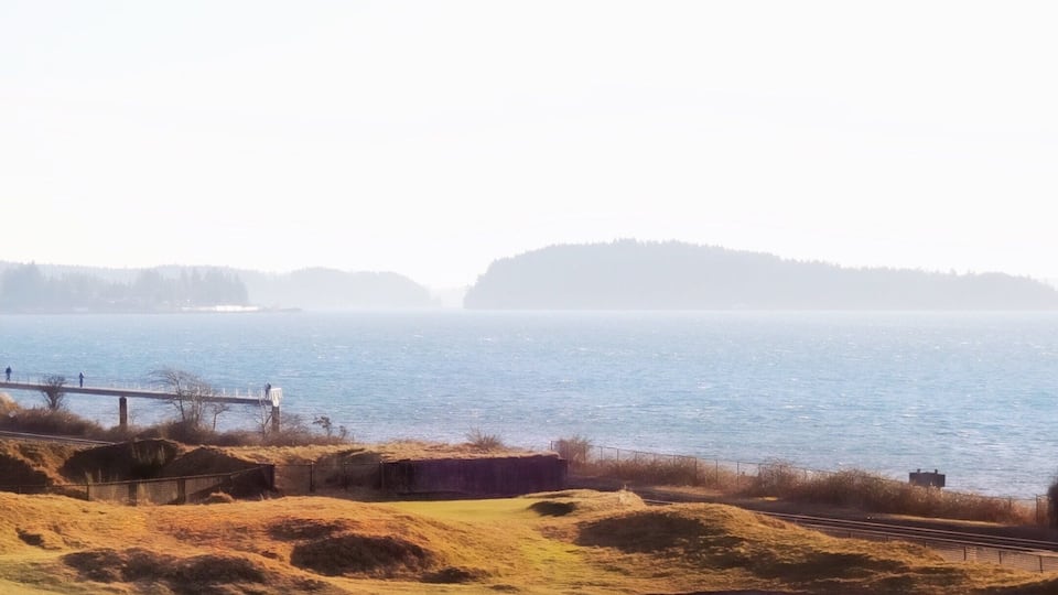 A golf course with a view of the sea and hills in the background.