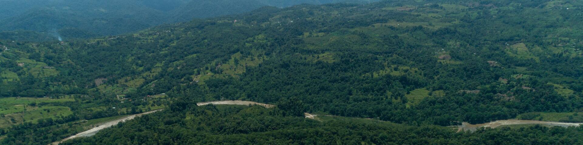 A lake surrounded by dense forest and rolling hills.