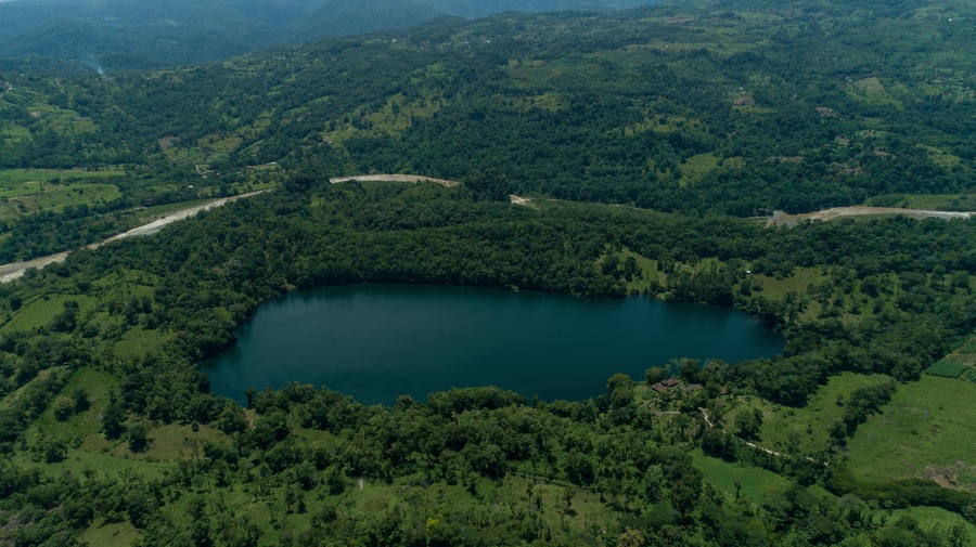 A lake surrounded by dense forest and rolling hills.