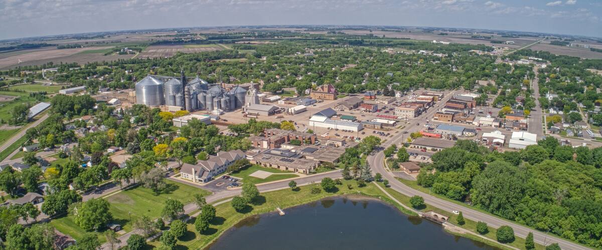 An aerial view of a town with a large lake, industrial buildings, and surrounding farmland.