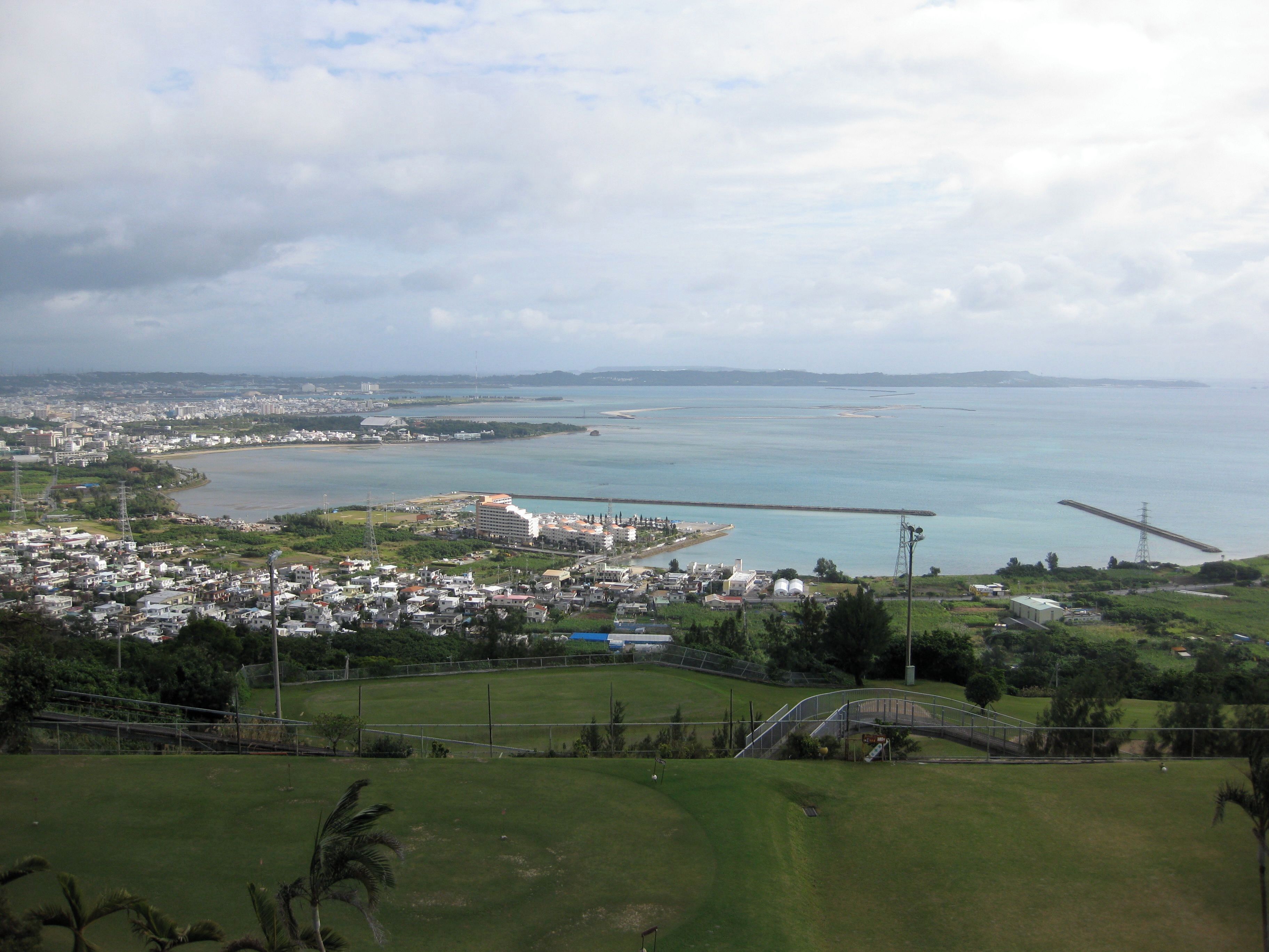 A coastal cityscape with a bridge, residential areas, and a large body of water.