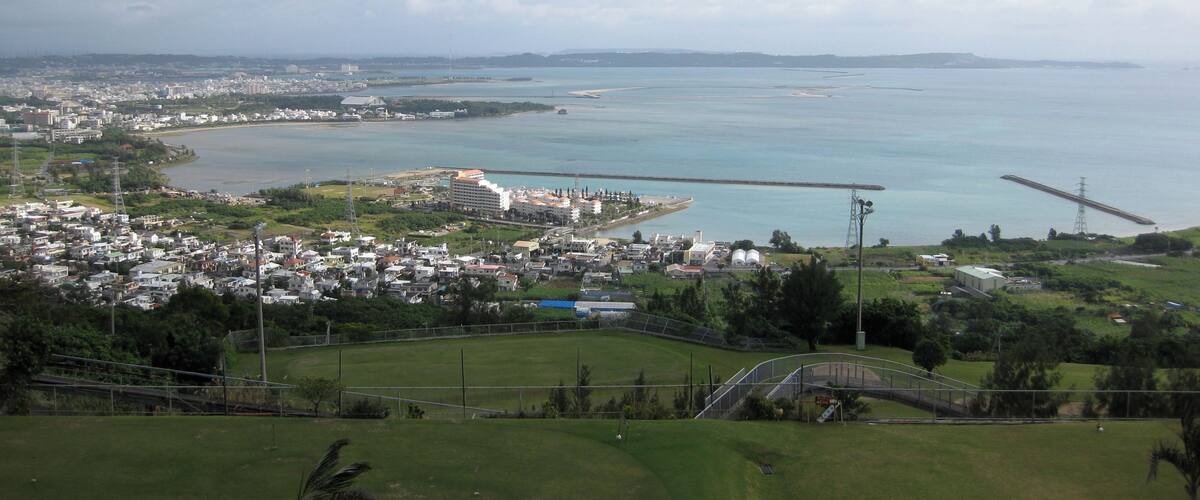 A coastal cityscape with a bridge, residential areas, and a large body of water.