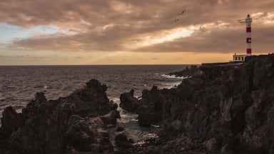 Litoral rochoso com farol e mar agitado.
