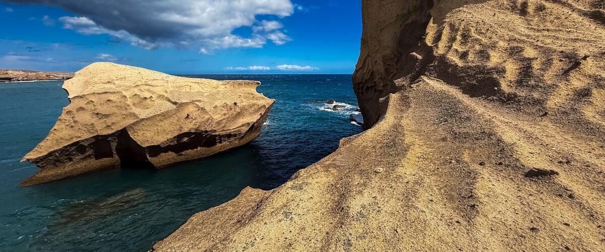 A coastal cliff with a boat in the water.