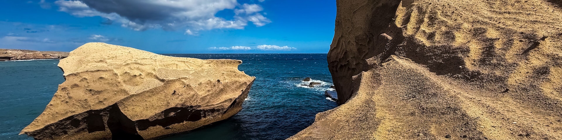 A coastal cliff with a boat in the water.