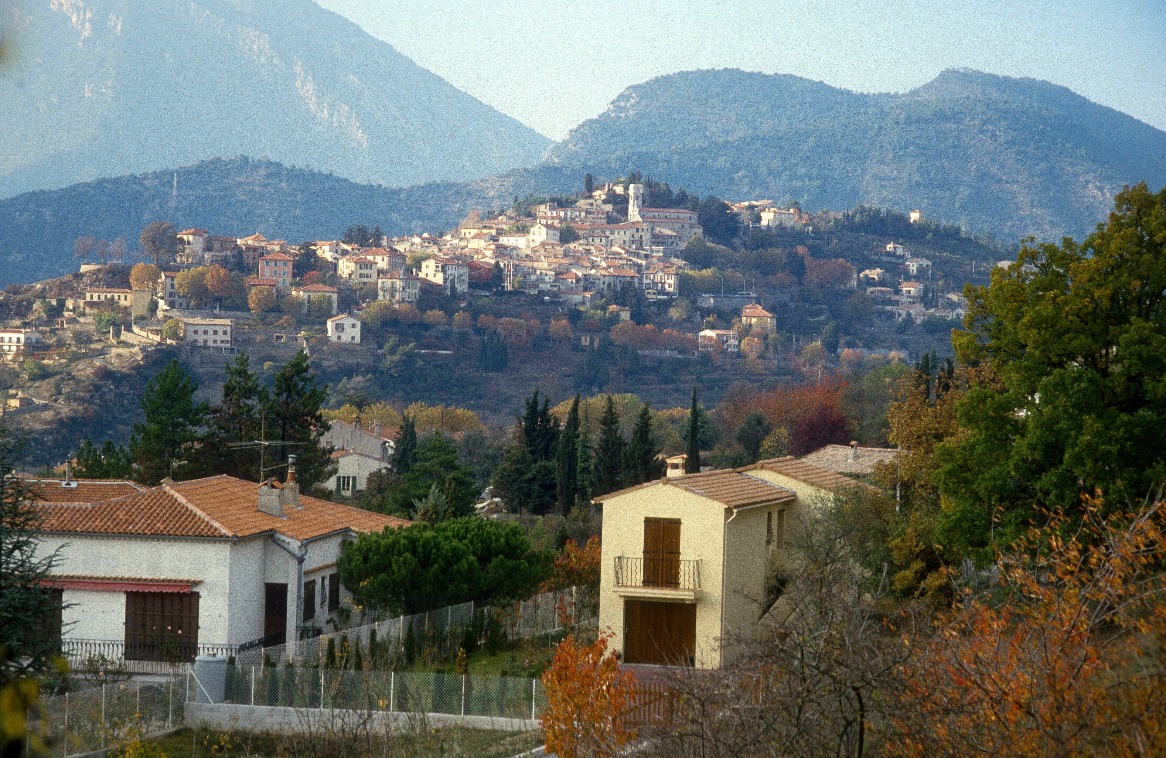 A mountainous town with buildings, a church, and autumn foliage.