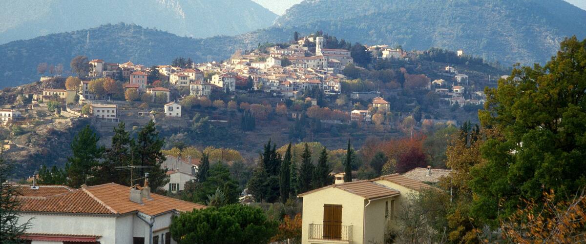 A mountainous town with buildings, a church, and autumn foliage.