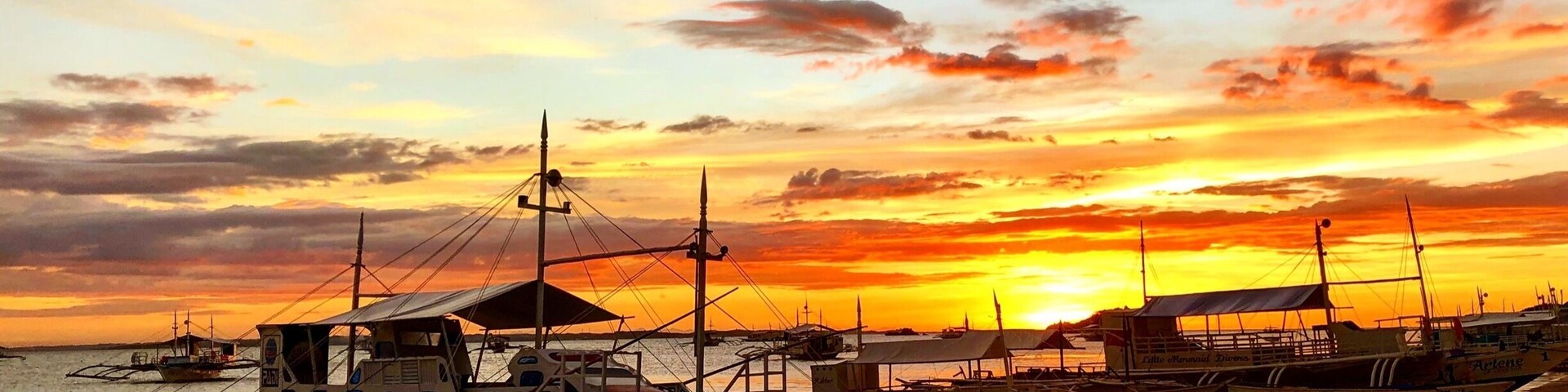 Un atardecer sobre un puerto con varias embarcaciones amarradas a la orilla.
