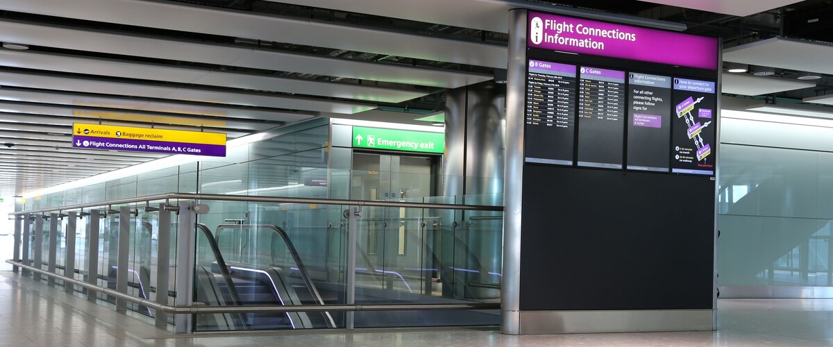 An airport terminal with signs for flight connections, baggage reclaim, and emergency exits.