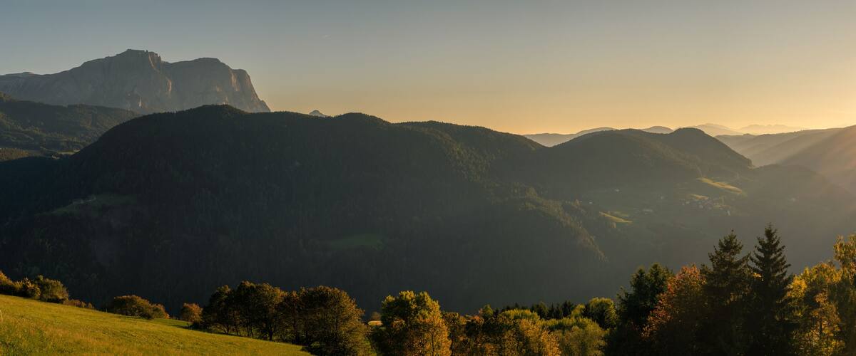A mountainous landscape with a valley and a forested area in the foreground.