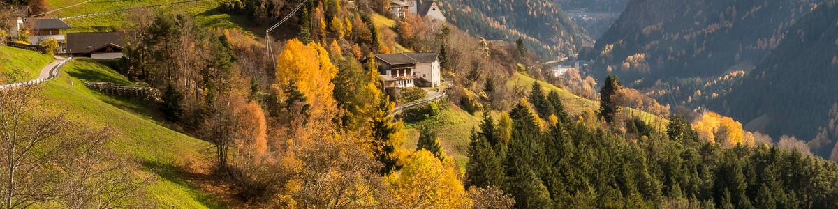 A valley with houses, autumn trees, and mountains.