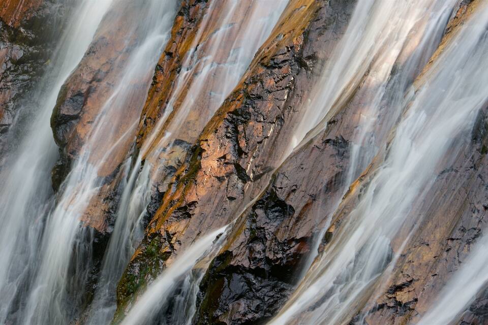 A waterfall cascading over rugged, moss-covered rocks.