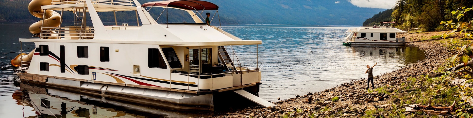 A family enjoying a houseboat vacation while parked on the shoreline of Shuswap Lake; Shuswap Lake, British Columbia, Canada