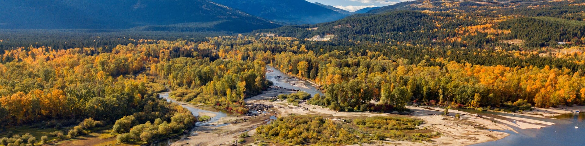 A river winding through a forested valley with mountains in the background.