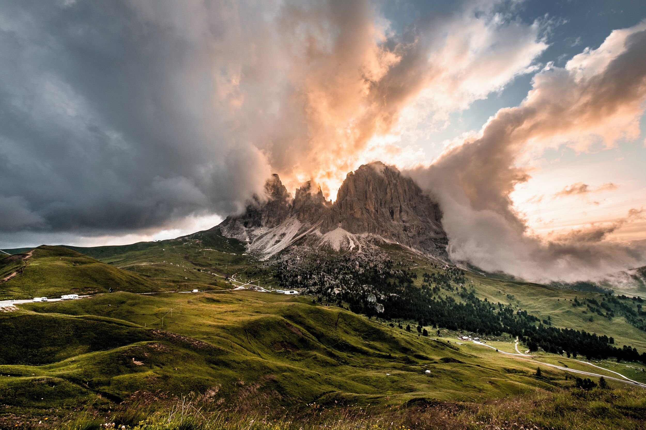 A mountainous landscape with a prominent peak, lush green valleys, and a winding road.