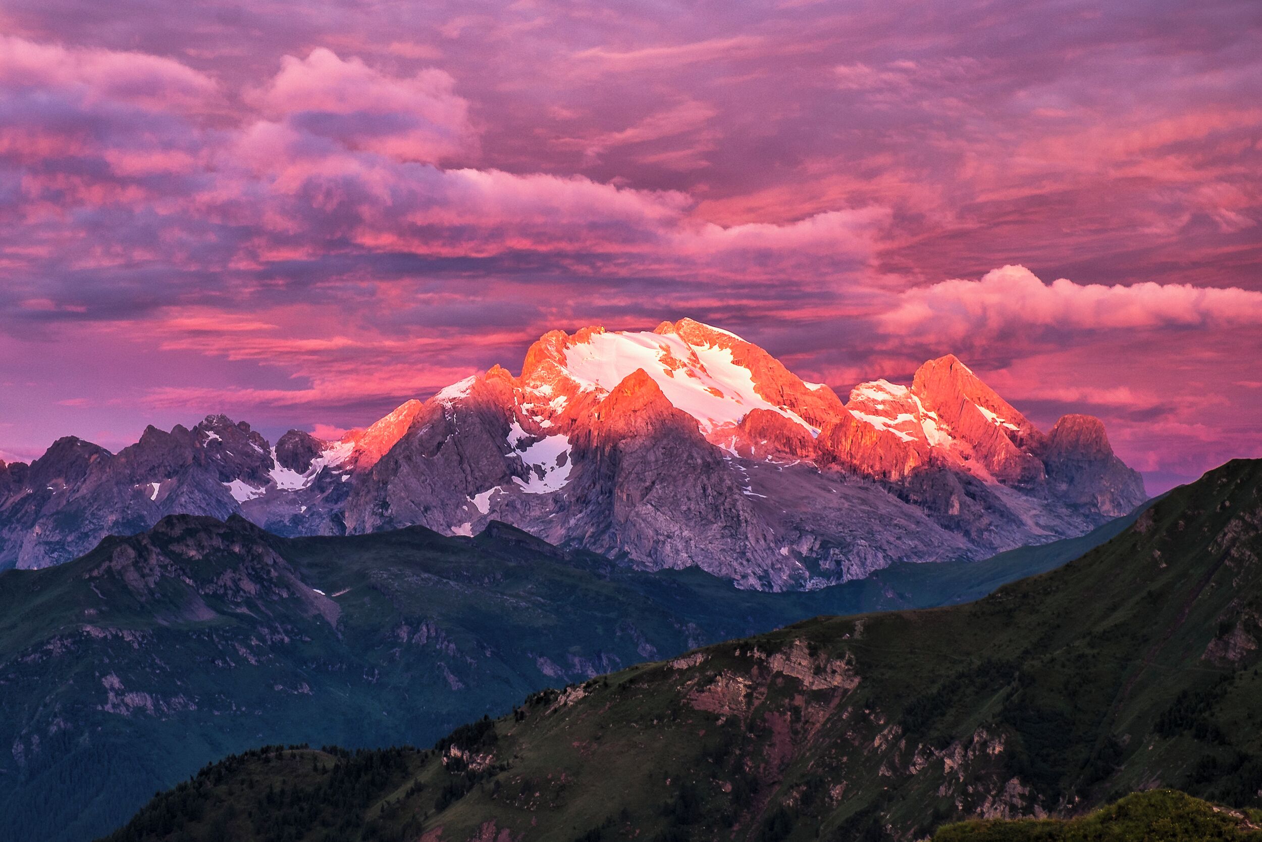 A mountain range with snow-capped peaks and a pinkish sky.