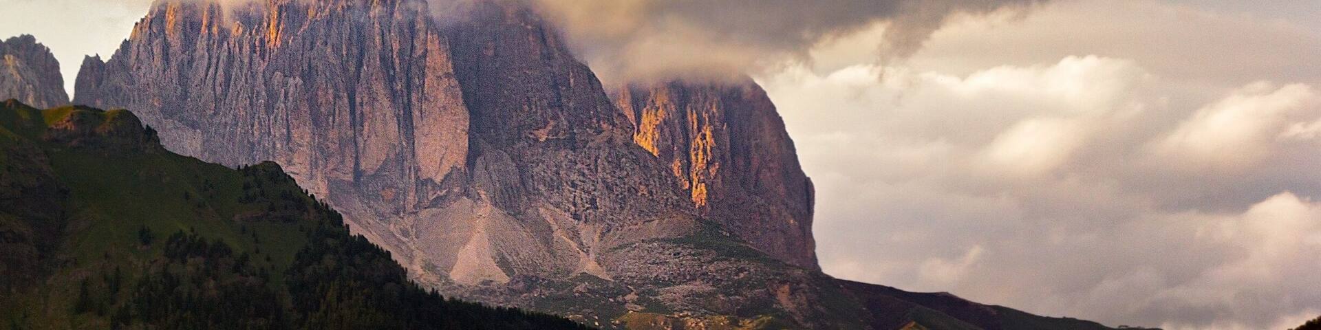A mountain with a cloud-covered peak and a green valley below.