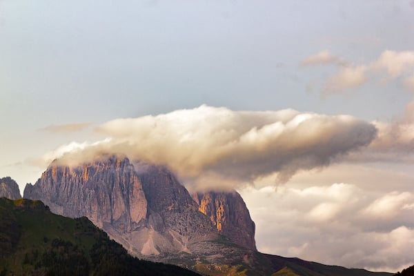 Ein Berg mit einem von Wolken bedeckten Gipfel und einem grünen Tal darunter.
