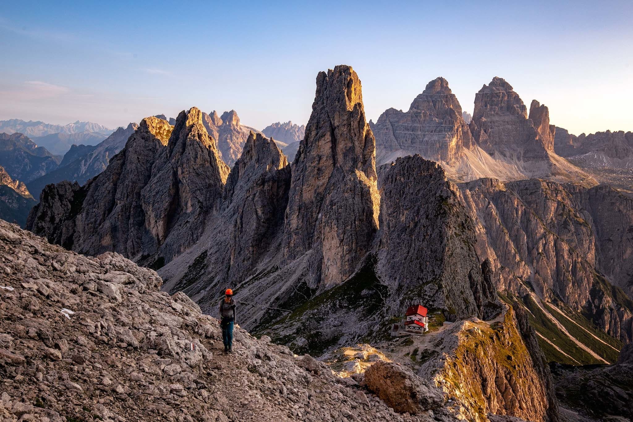 A mountainous landscape with rugged peaks and a person standing on a rocky outcrop.