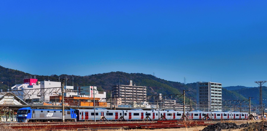 JR Freight Class EF210 electric locomotive EF210-901 hauling JR Kyushu 821 series EMU sets U001 (rear) and U002 (front) at Shinnan-yo Station on the Sanyo Main Line on delivery from the Hitachi factory in Kudamatsu, Japan