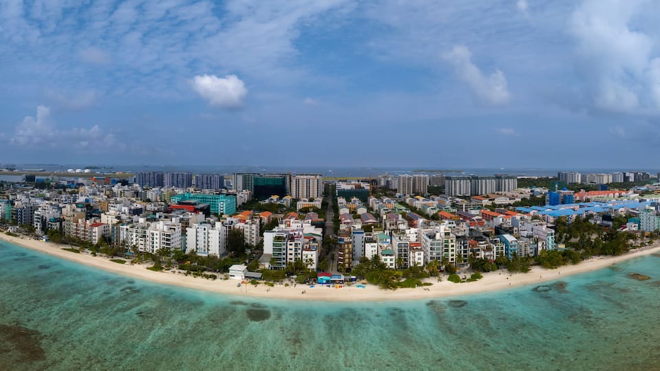 A coastal cityscape with a beach, high-rise buildings, and a clear sky.