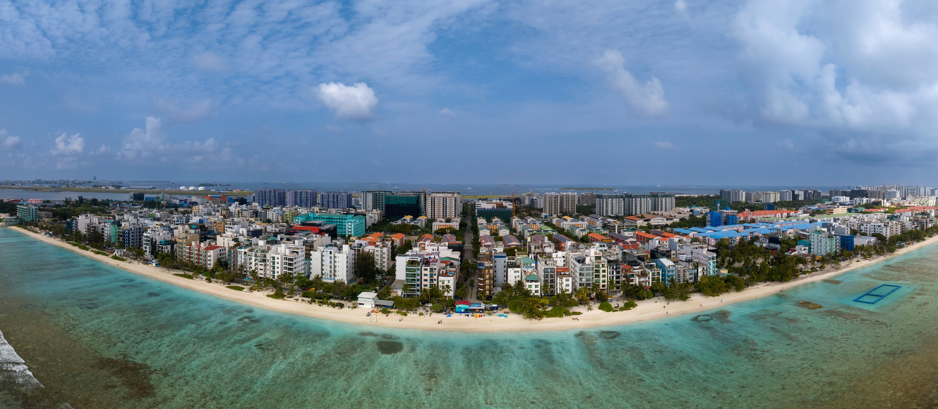 A coastal cityscape with a beach, high-rise buildings, and a clear sky.