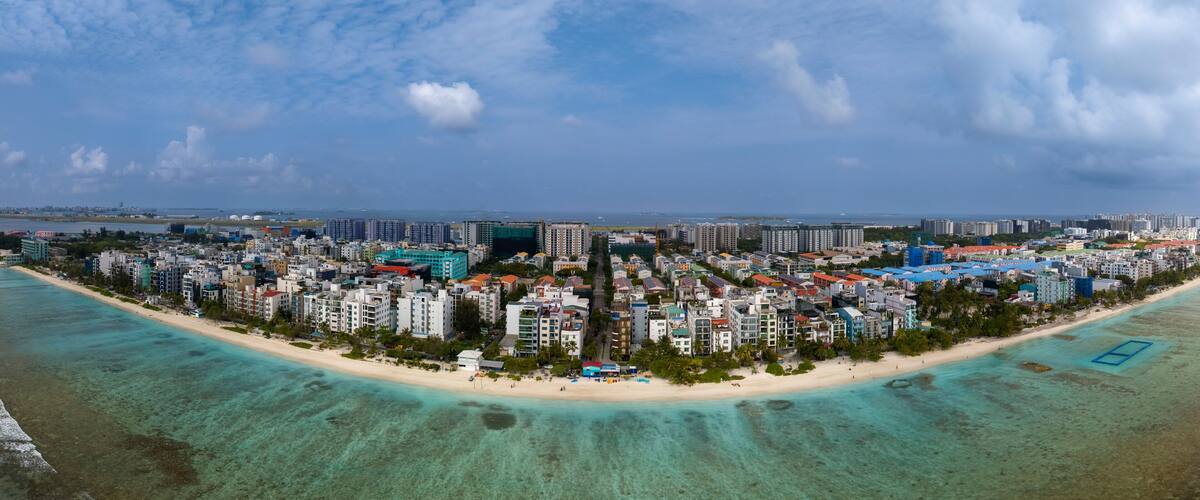 A coastal cityscape with a beach, high-rise buildings, and a clear sky.