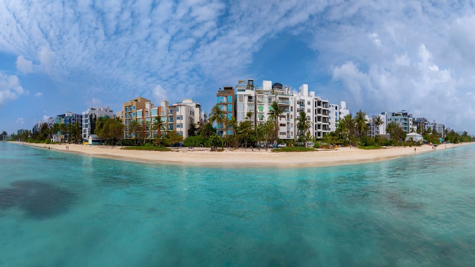 A coastal resort with a beach, clear turquoise waters, and a cluster of modern buildings.