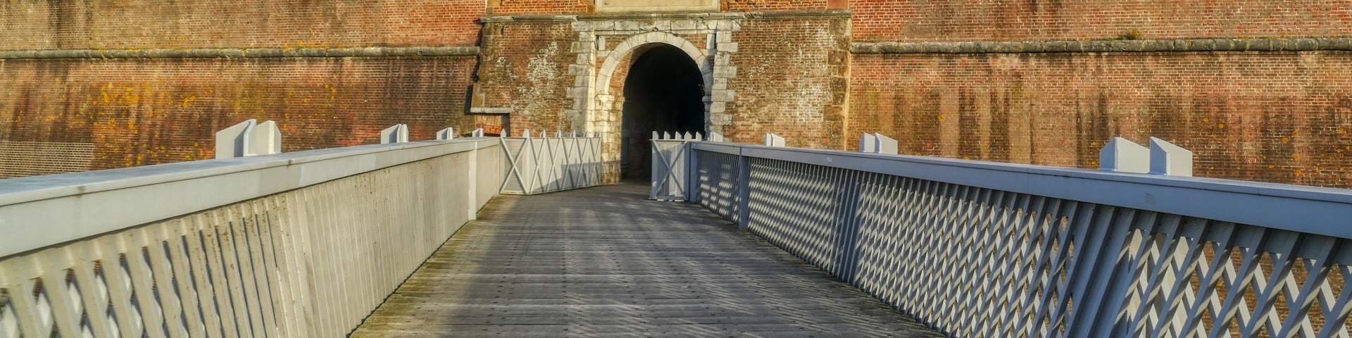 Uma ponte de madeira com uma parede de tijolos e a entrada de um túnel.