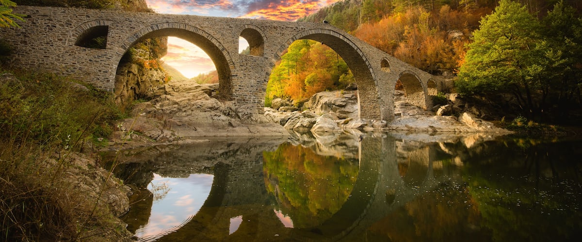Devil's bridge at Ardino, Bulgaria. Ancient stone bridge at autumn forest at sunset. Ottoman Architecture near the town of Ardino, Rhodope Mountains and Arda river, Kardzhali Region