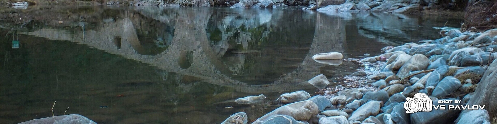 The Dyavolski Most (Devil’s Bridge), (also known as Sheytan Kyupriya) is a medieval bridge over the Arda river in Bulgaria. It is situated in a picturesque valley about 10 kilometers northwest of the town of Ardino and 4 kilometers east of the village of Galabovo (municipality of Banite).
The bridge was built in 1515 - 1518 by the builder Dimitar from the village of Nedelino (which is a town nowadays) upon the remains of an ancient Roman bridge on the road, linking the Aegean region with Northern Thracian valley (Gornotrakiyski Nizina) through the Makaza pass.
The bridge is situated 420 meters above sea level and is surrounded on both sides by steep slopes. Its length is 56 meters, and its width is 3.5. The bridge has three vaults; it has holes with small arches in its side vaults, made for drainage. The height of the middle vault is 11.5 - 12 meters, with a stone parapet on the edge, 12 cm high.
In 1984 the bridge was declared a cultural monument. The bridge can be reached by car, passing along a rough road. Tourist infrastructure had been built near it for picnic and recreation.
