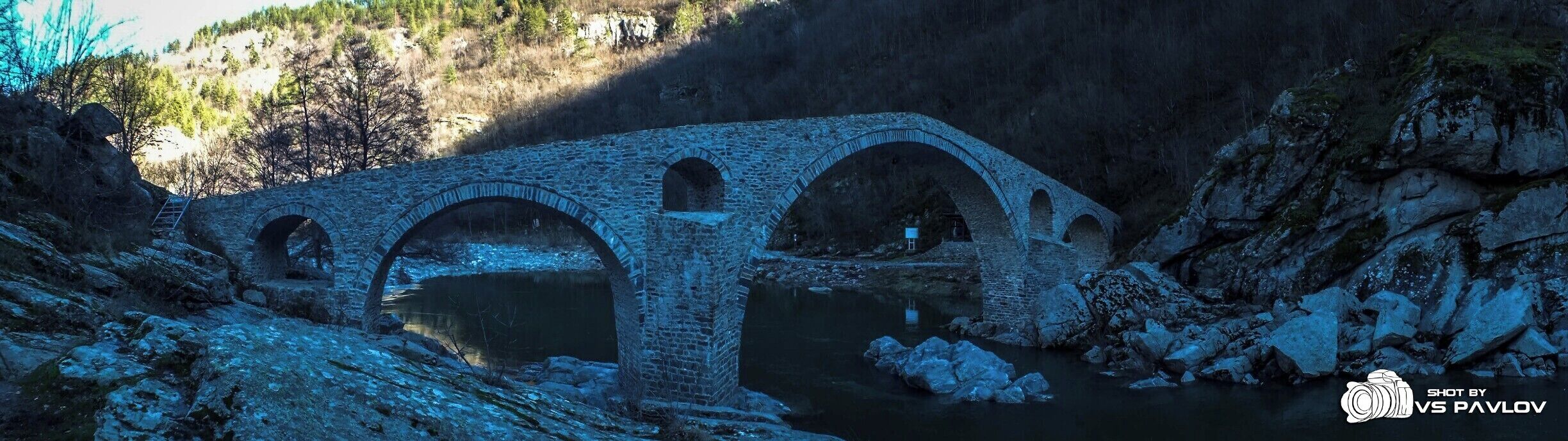 The Dyavolski Most (Devil’s Bridge), (also known as Sheytan Kyupriya) is a medieval bridge over the Arda river in Bulgaria. It is situated in a picturesque valley about 10 kilometers northwest of the town of Ardino and 4 kilometers east of the village of Galabovo (municipality of Banite).

The bridge was built in 1515 - 1518 by the builder Dimitar from the village of Nedelino (which is a town nowadays) upon the remains of an ancient Roman bridge on the road, linking the Aegean region with Northern Thracian valley (Gornotrakiyski Nizina) through the Makaza pass.

The bridge is situated 420 meters above sea level and is surrounded on both sides by steep slopes. Its length is 56 meters, and its width is 3.5. The bridge has three vaults; it has holes with small arches in its side vaults, made for drainage. The height of the middle vault is 11.5 - 12 meters, with a stone parapet on the edge, 12 cm high.

In 1984 the bridge was declared a cultural monument. The bridge can be reached by car, passing along a rough road. Tourist infrastructure had been built near it for picnic and recreation.