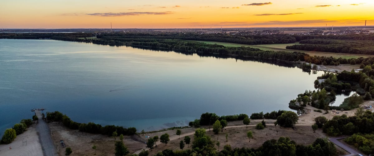 A large body of water surrounded by greenery and a small settlement.