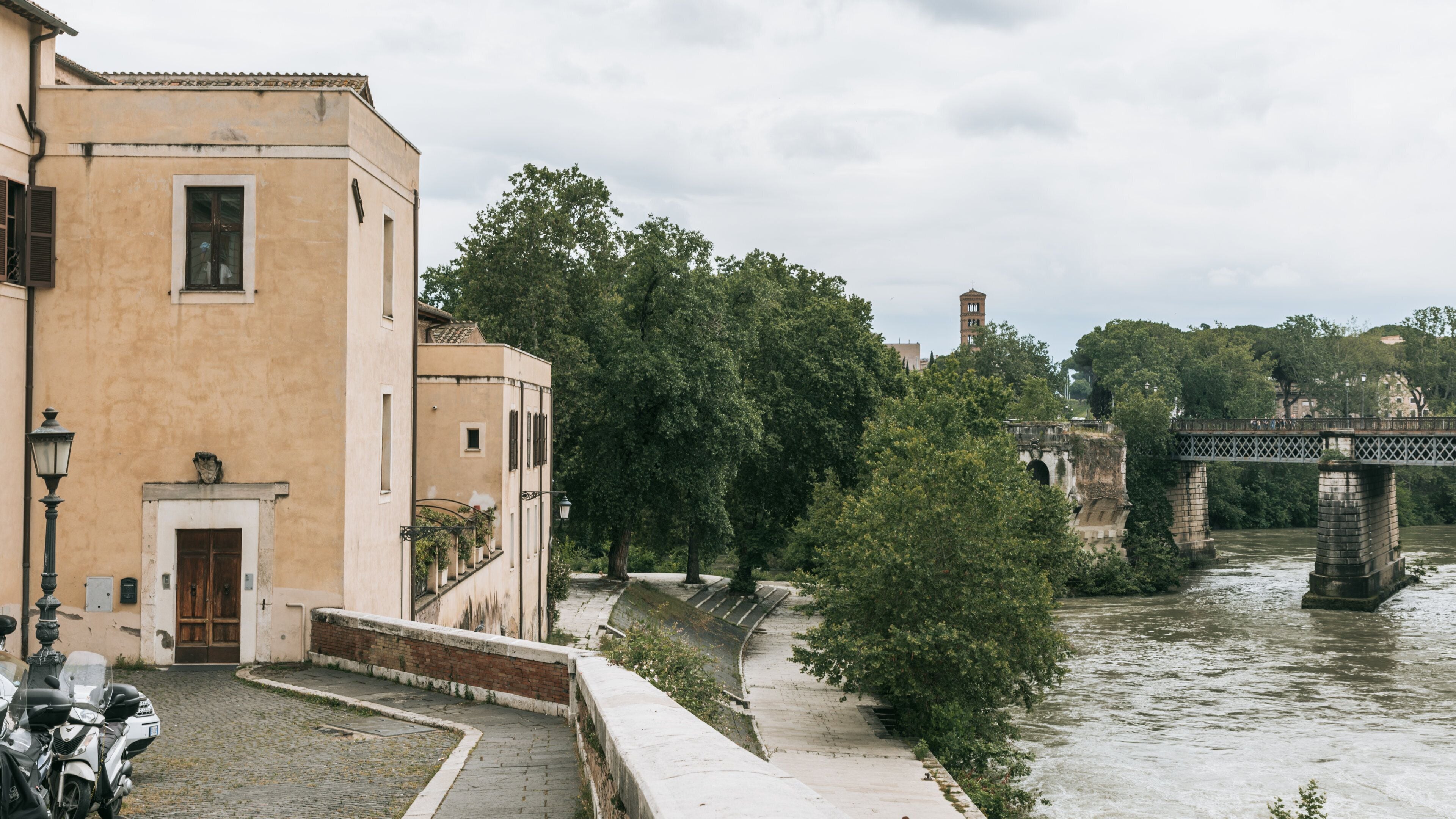 Un fiume con un ponte, un edificio con una porta e alberi lungo la riva.
