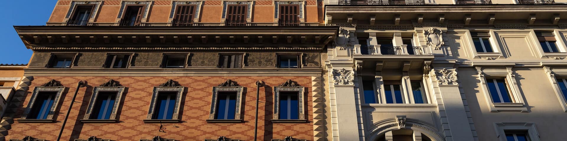 Light and shadow reveal the intricate facades of historic buildings on Via del Tritone in Rome city centre, Italy