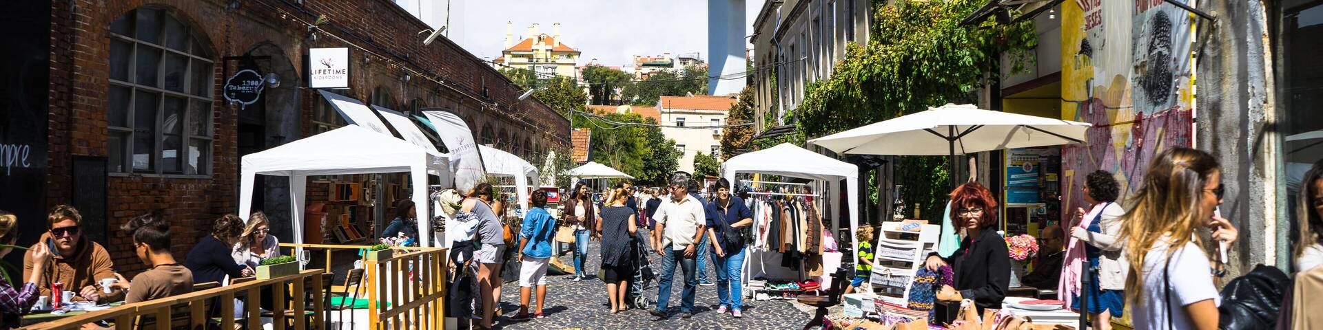 A cobblestone street with outdoor market stalls and brick buildings.