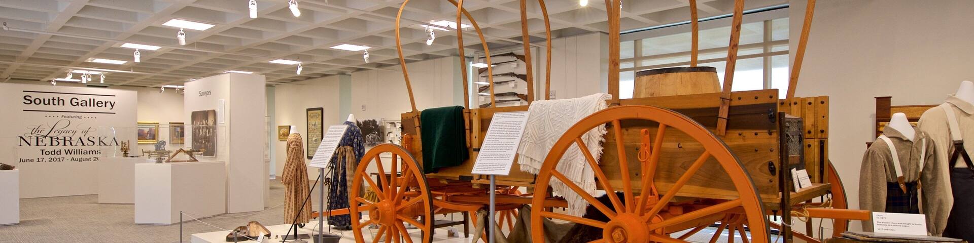 Exposición de antiguos carros y artefactos relacionados en una galería.