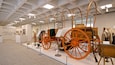 An exhibition of antique wagons and related artifacts in a gallery.
