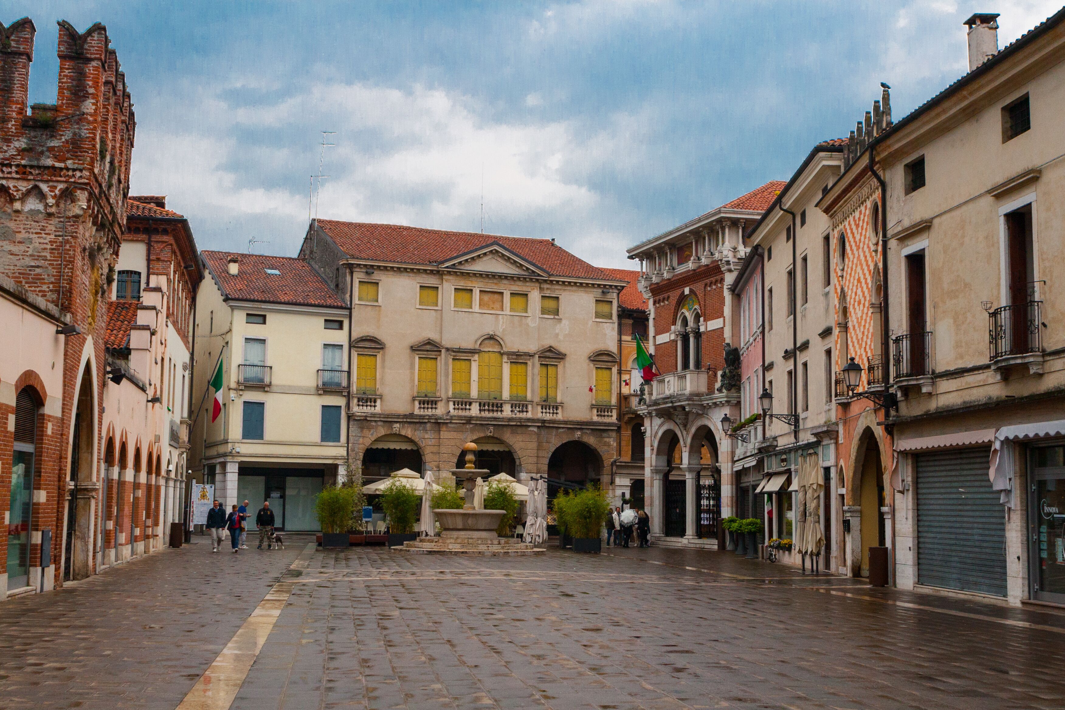 A historic square with cobblestone pavement, traditional European architecture, and a fountain.