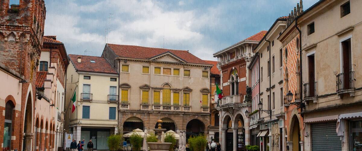 A historic square with cobblestone pavement, traditional European architecture, and a fountain.