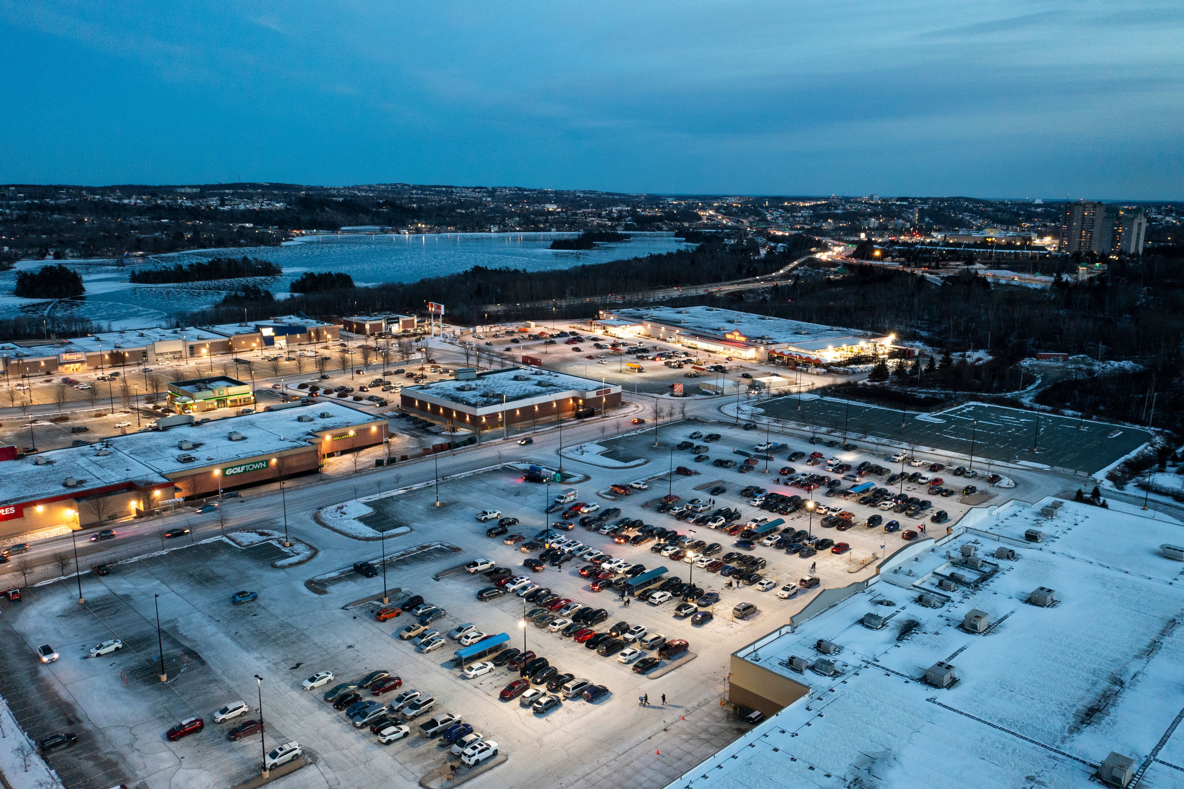 Aerial view of illuminated shopping center and parking lot with vehicles in winter, Dartmouth Crossing, Canada.