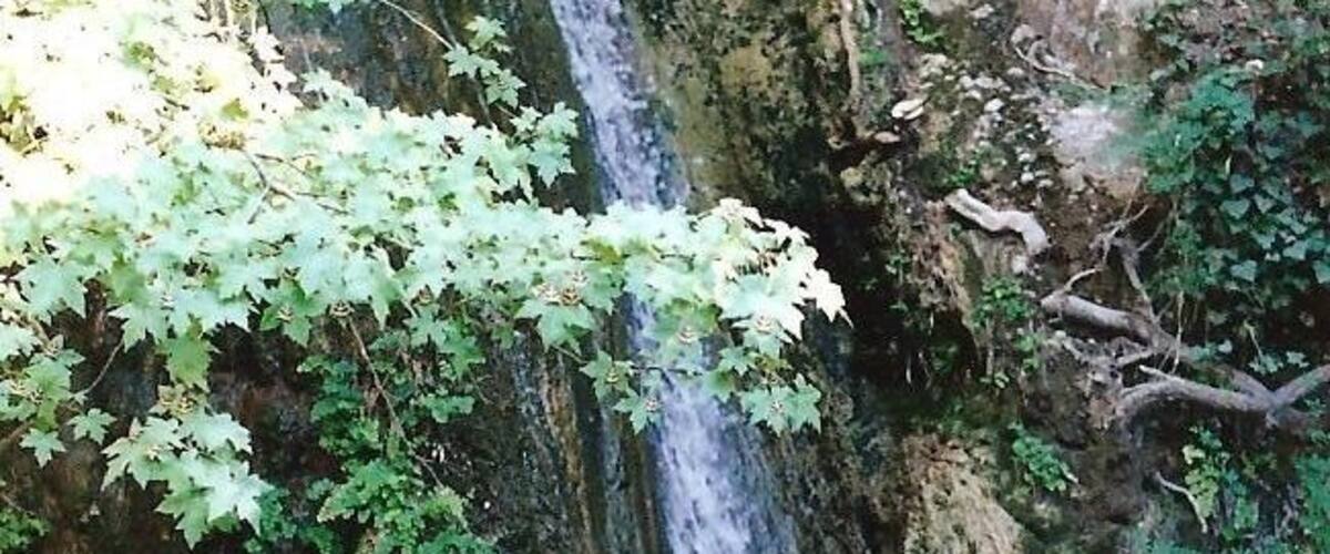 A waterfall cascading down a rocky cliff with green foliage.