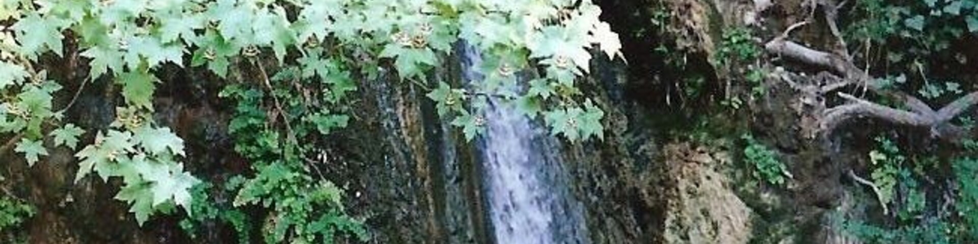 A waterfall cascading down a rocky cliff with green foliage.