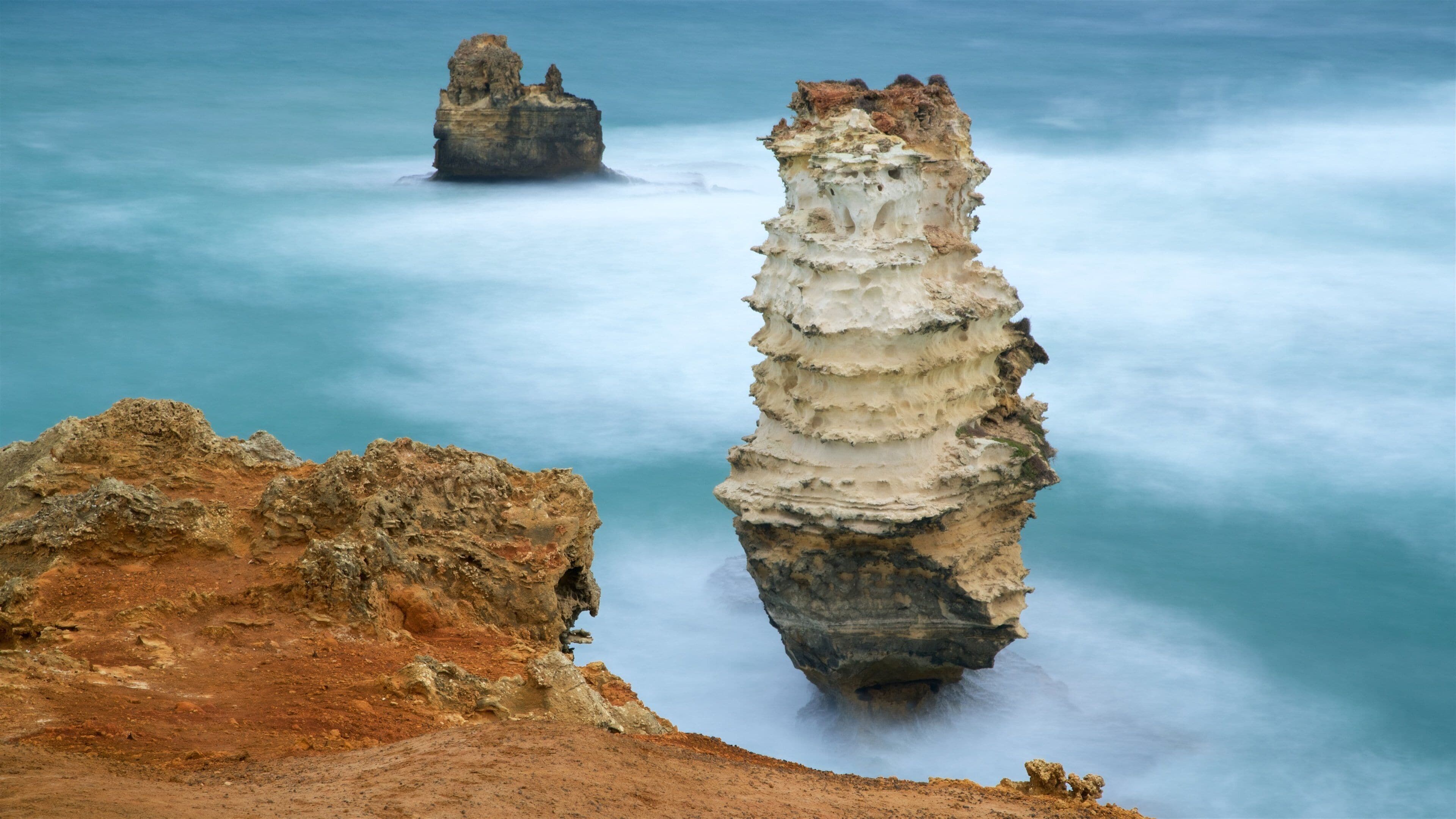 A coastal landscape with prominent rock formations and a calm sea.
