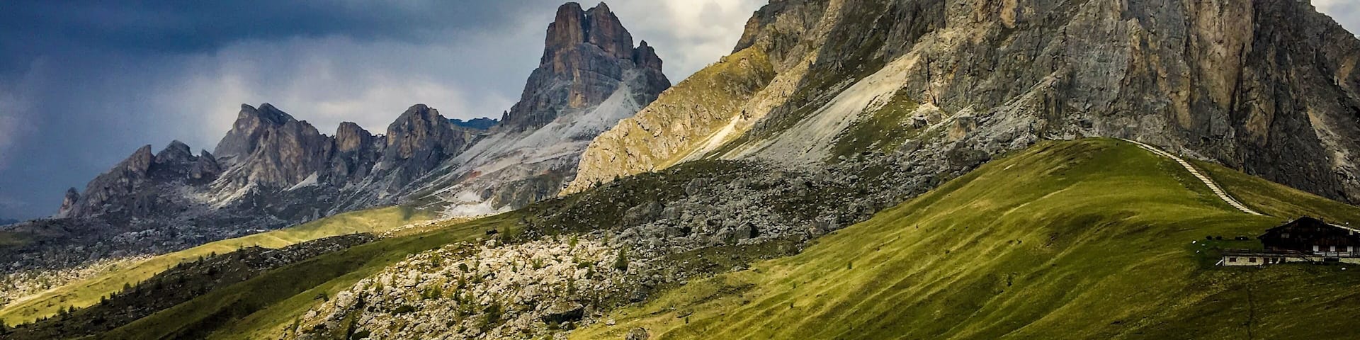 A mountain range with prominent peaks and a small building in the foreground.